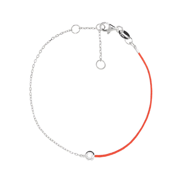 Silver chain and red string bracelet with a small cubic zirconia stone laid out in a circular shape.